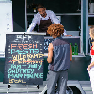 Silver Presentation Easel with signage being held on the front of a food truck. 