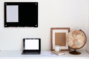 Wall Mounted Black Magnetic Board in a home office with a laptop shown underneath.  Includes 2 Neodymium Magnets holding a paper and expo neon markers stored in the included marker tray. 