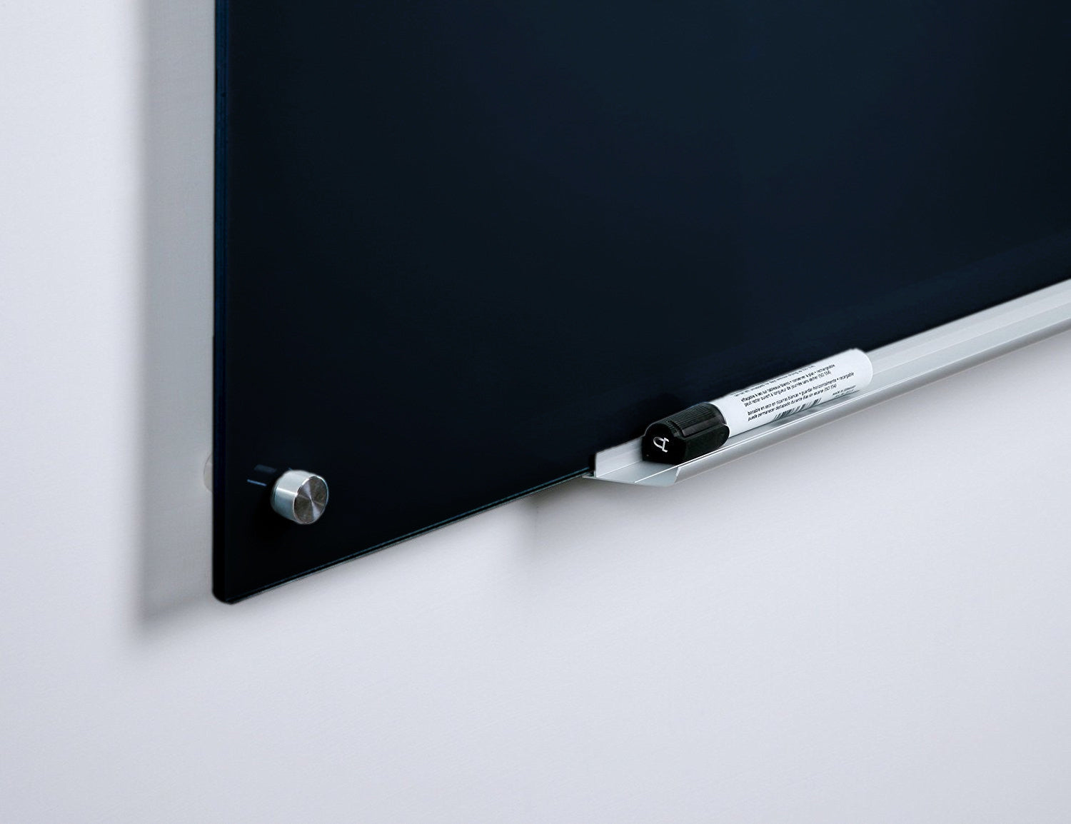 Black Glass Dry-Erase Board with Aluminum Marker Tray. Close up to show frameless design along with rounded corners and black glass color. 