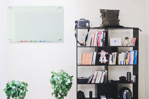 Frosted Glass Dry-Erase Board with Aluminum Marker Tray (Non-Magnetic). 18" x 24" Wall Mounted in a living room with marker tray and dry erase pens. 