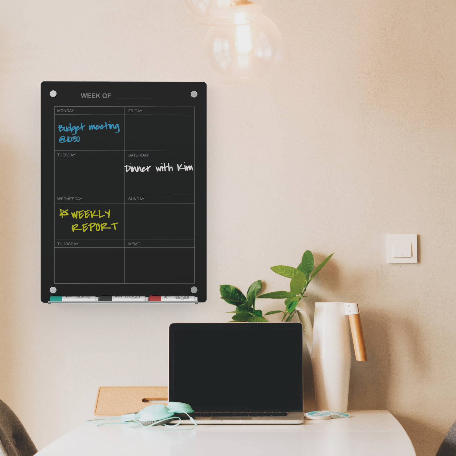 Black glass weekly planner wall mounted in a home office.